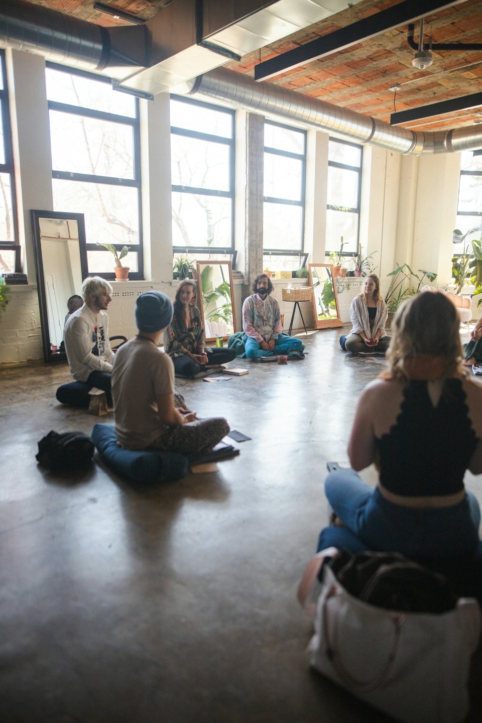 Young adults in a circle discussing ideas on a concrete floor.