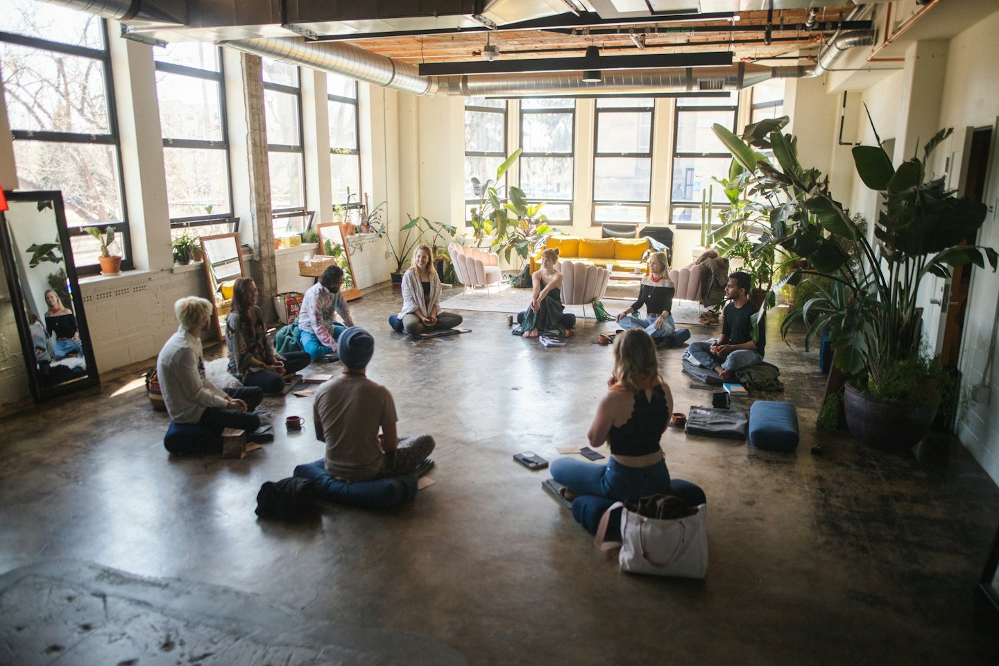 Diverse young adults discussing ideas on a concrete floor workshop space.